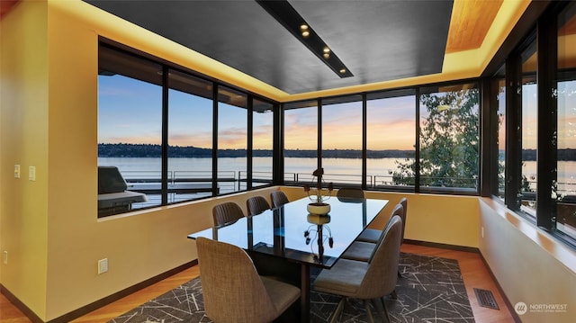 dining area with a water view, wood finished floors, visible vents, and baseboards