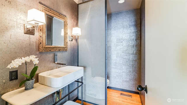 bathroom featuring toilet, wood finished floors, a sink, and visible vents