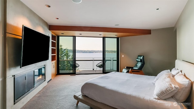 bedroom featuring light carpet, a glass covered fireplace, and access to exterior