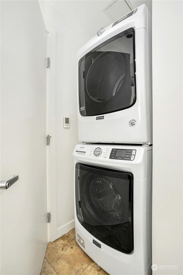 laundry area with stacked washer and dryer and light tile patterned flooring