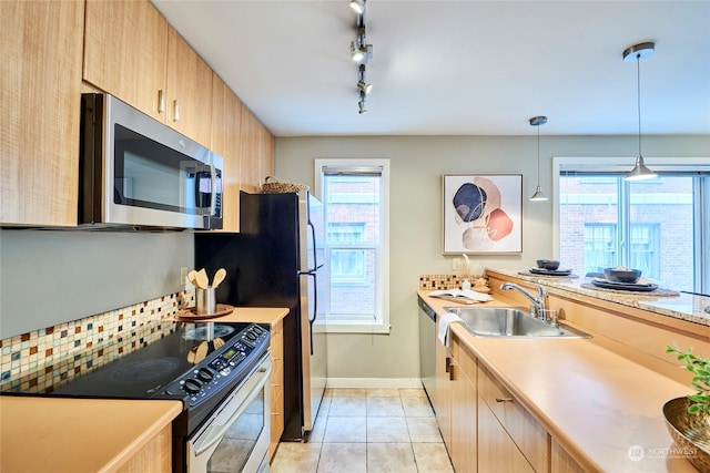 kitchen featuring pendant lighting, sink, light tile patterned floors, light brown cabinetry, and stainless steel appliances