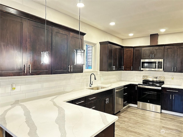 kitchen with sink, light stone counters, dark brown cabinets, appliances with stainless steel finishes, and pendant lighting