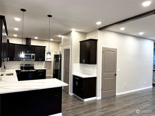 kitchen with appliances with stainless steel finishes, dark hardwood / wood-style floors, sink, hanging light fixtures, and dark brown cabinetry