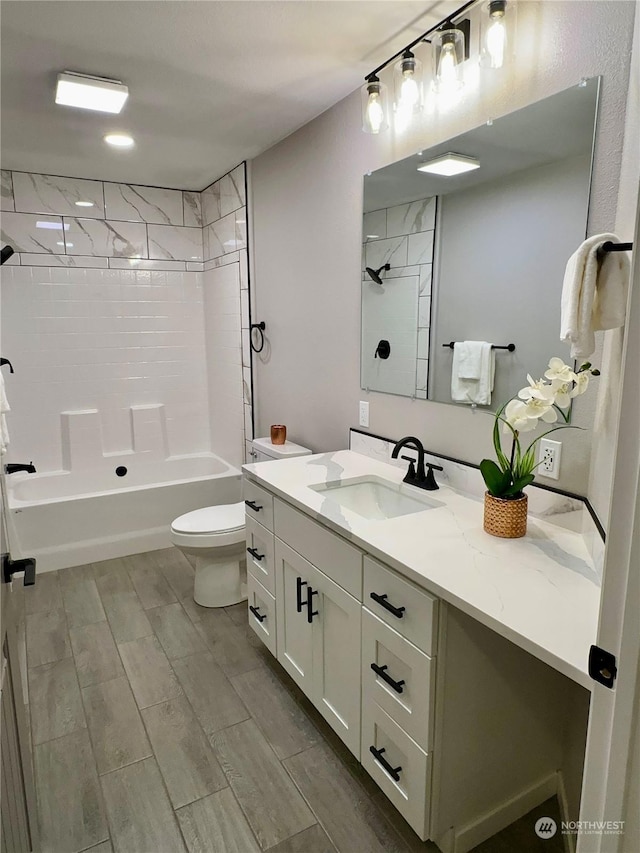 full bathroom featuring vanity, tiled shower / bath, and toilet