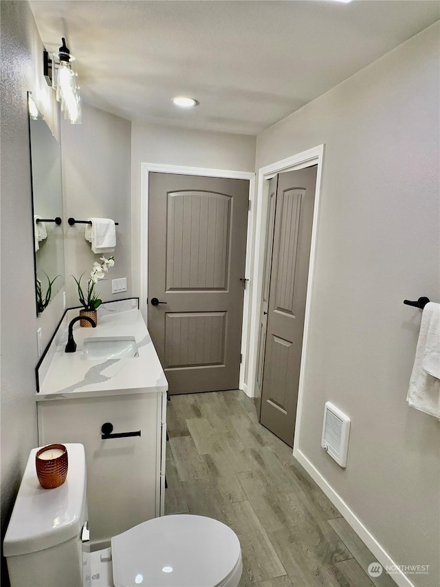 bathroom featuring hardwood / wood-style flooring, vanity, and toilet