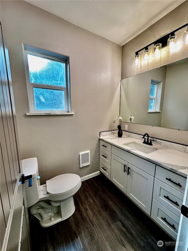 bathroom with vanity, a healthy amount of sunlight, hardwood / wood-style flooring, and toilet