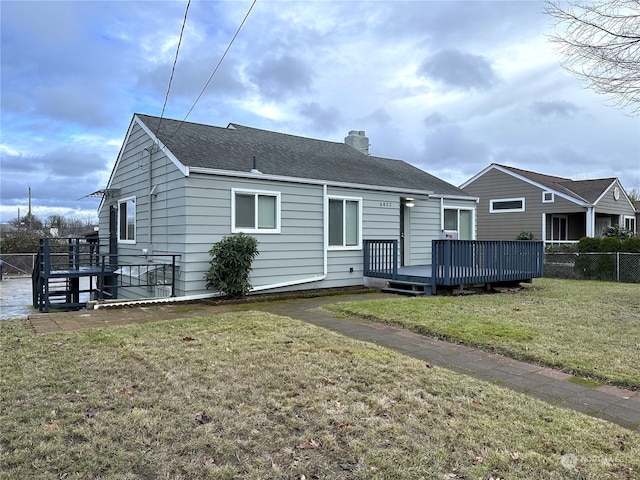 rear view of house with a lawn and a wooden deck