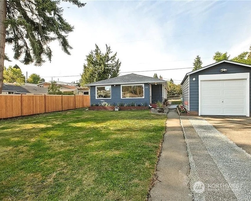 single story home with a garage, an outdoor structure, and a front lawn