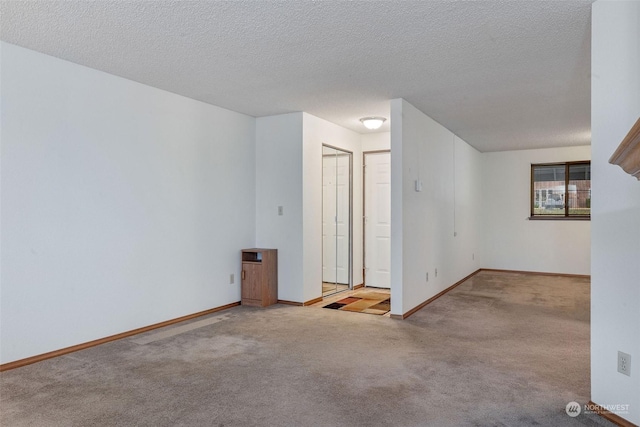 empty room featuring baseboards, carpet floors, and a textured ceiling