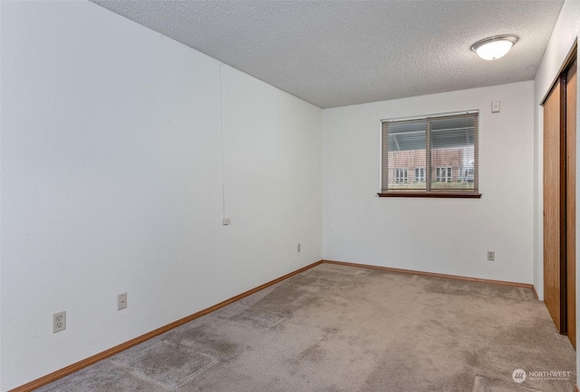 carpeted spare room with baseboards and a textured ceiling