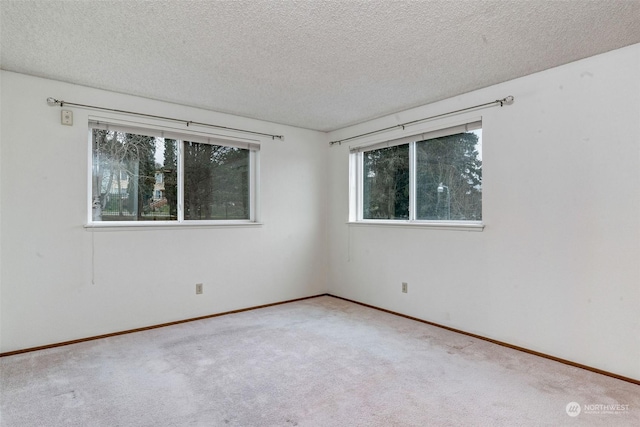 carpeted empty room with baseboards and a textured ceiling