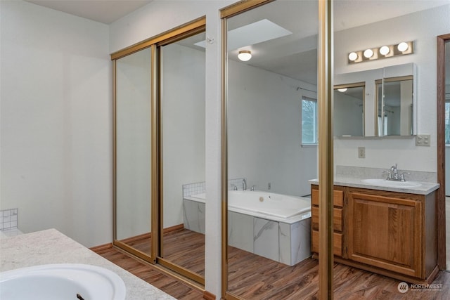 full bathroom featuring vanity, a bath, wood finished floors, and a stall shower