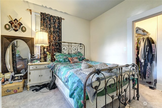 bedroom with light colored carpet, a closet, and a walk in closet