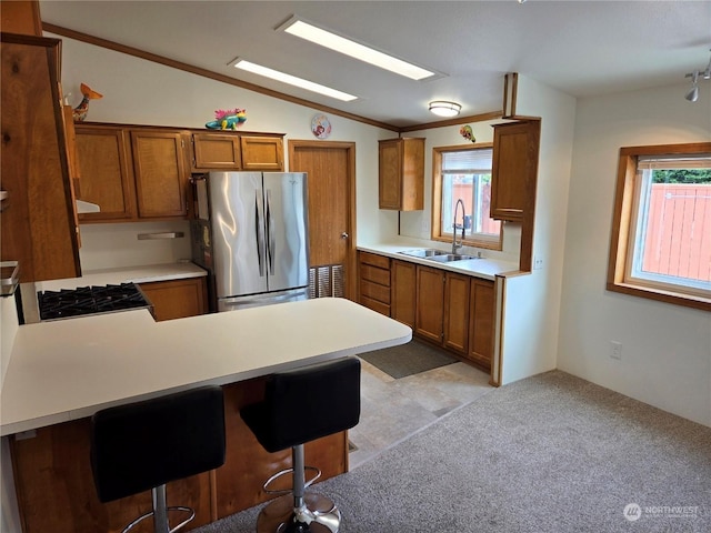 kitchen featuring a breakfast bar, lofted ceiling, sink, stainless steel fridge, and kitchen peninsula