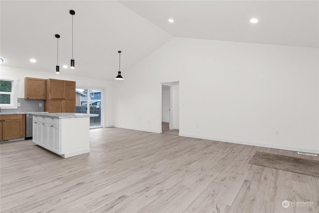 kitchen with stainless steel dishwasher, decorative backsplash, light wood-type flooring, decorative light fixtures, and a kitchen island