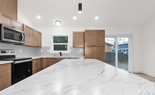 kitchen featuring stainless steel appliances, a healthy amount of sunlight, sink, decorative light fixtures, and lofted ceiling