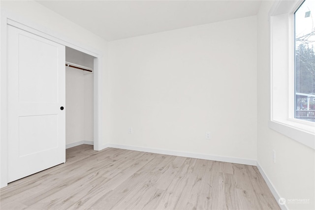 unfurnished bedroom with a closet and light hardwood / wood-style floors