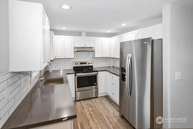 kitchen with sink, stainless steel appliances, light hardwood / wood-style floors, decorative backsplash, and white cabinets