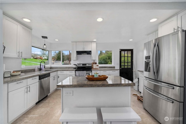 kitchen featuring appliances with stainless steel finishes, a kitchen island, sink, white cabinetry, and plenty of natural light