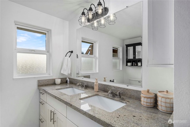 bathroom featuring a notable chandelier, vanity, and toilet