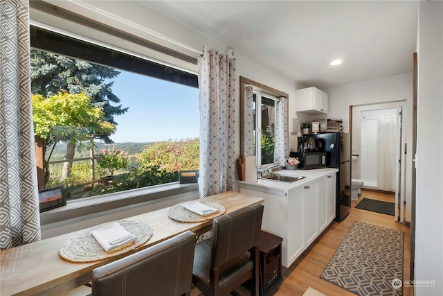 kitchen with white cabinetry, black appliances, a healthy amount of sunlight, and sink