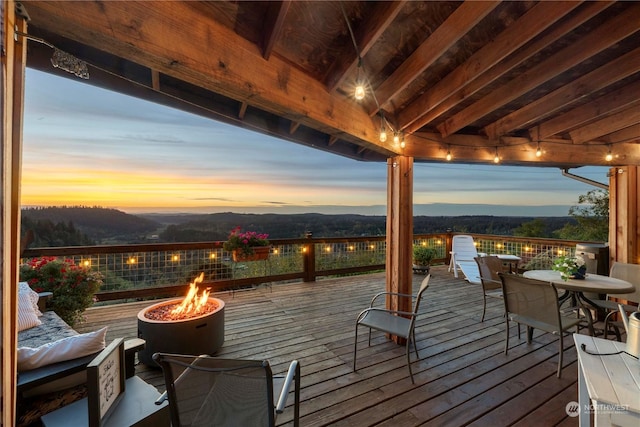 deck at dusk featuring a mountain view and an outdoor fire pit