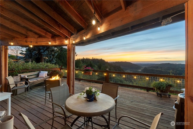 deck at dusk featuring a mountain view and an outdoor fire pit