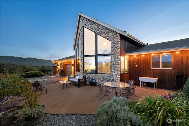 back house at dusk featuring a mountain view, a fire pit, and a patio area