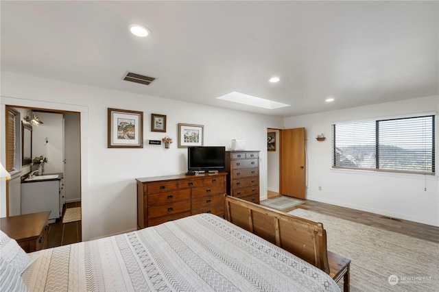 bedroom featuring hardwood / wood-style flooring, sink, and a skylight