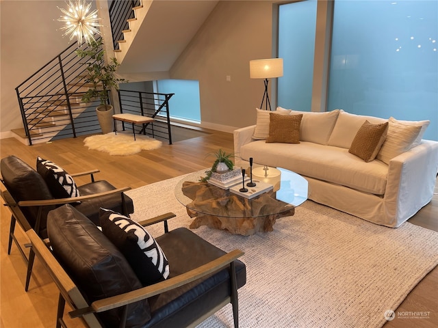 living room featuring a chandelier, hardwood / wood-style flooring, and lofted ceiling