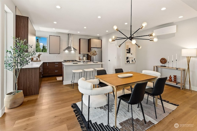 dining area featuring light hardwood / wood-style floors, an AC wall unit, and a chandelier