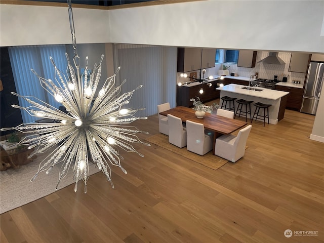 dining space featuring sink, light hardwood / wood-style flooring, and a chandelier