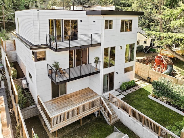 back of property with a balcony, a wall unit AC, and a lawn