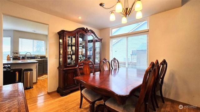 dining space with sink, light hardwood / wood-style flooring, plenty of natural light, and an inviting chandelier