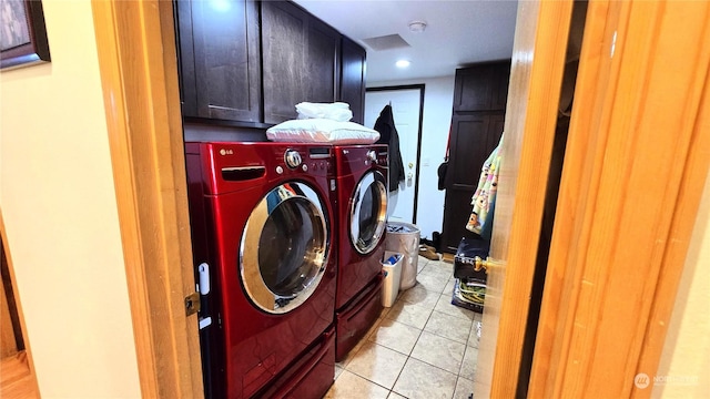 laundry area with cabinets, light tile patterned floors, and washing machine and dryer