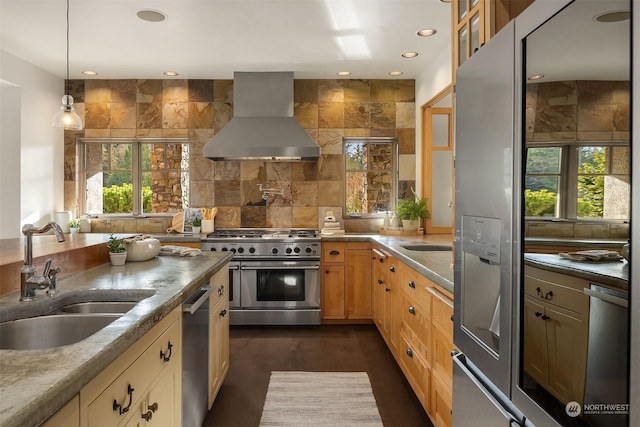 kitchen with decorative light fixtures, sink, stainless steel appliances, and wall chimney range hood