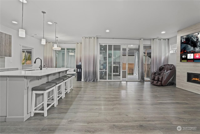 kitchen featuring a breakfast bar, sink, an island with sink, decorative light fixtures, and a fireplace