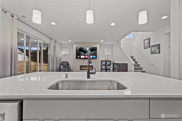 kitchen featuring decorative light fixtures, sink, and a kitchen island with sink