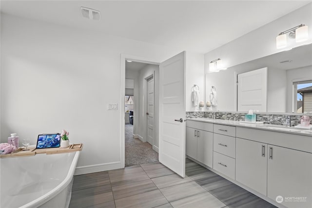 bathroom featuring vanity, a tub to relax in, and tasteful backsplash