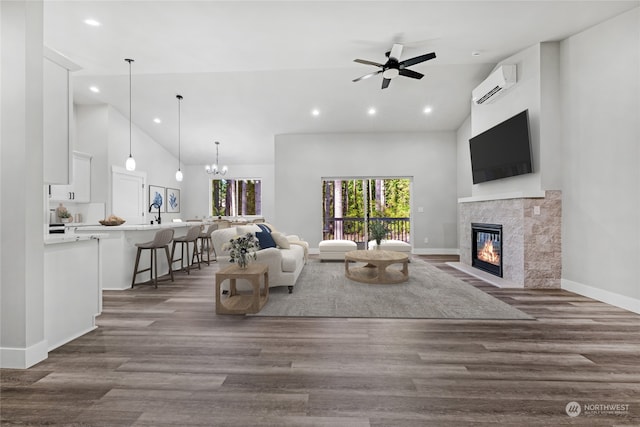 living room featuring a tile fireplace, dark hardwood / wood-style flooring, an AC wall unit, and ceiling fan with notable chandelier