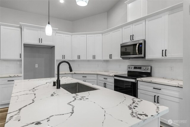 kitchen with white cabinetry, sink, stainless steel appliances, and decorative light fixtures