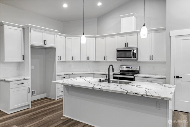 kitchen featuring pendant lighting, an island with sink, appliances with stainless steel finishes, light stone counters, and white cabinetry