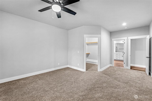 unfurnished bedroom featuring carpet flooring, a walk in closet, ensuite bathroom, ceiling fan, and a closet