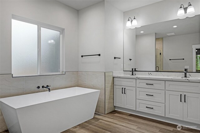 bathroom featuring shower with separate bathtub, vanity, hardwood / wood-style flooring, and tile walls