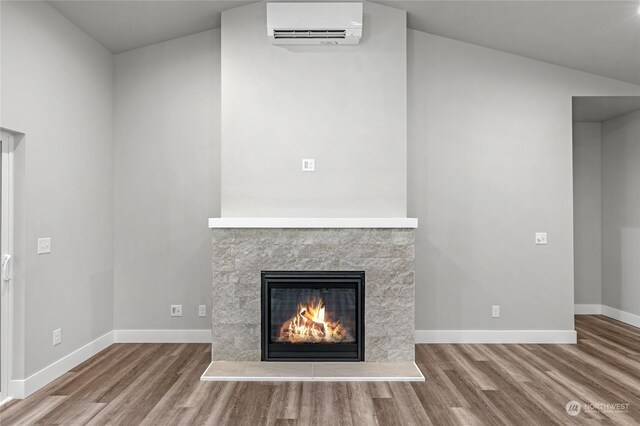 unfurnished living room with a tile fireplace, hardwood / wood-style flooring, a wall unit AC, and lofted ceiling