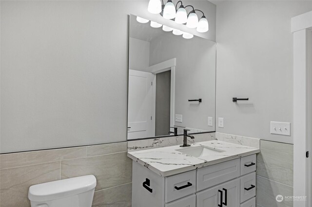 bathroom featuring vanity, tile walls, and toilet