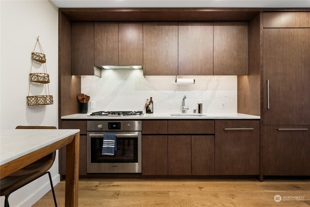 kitchen with decorative backsplash, light hardwood / wood-style floors, sink, and stainless steel appliances