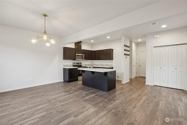 kitchen featuring a chandelier, appliances with stainless steel finishes, light wood-type flooring, dark brown cabinetry, and decorative light fixtures