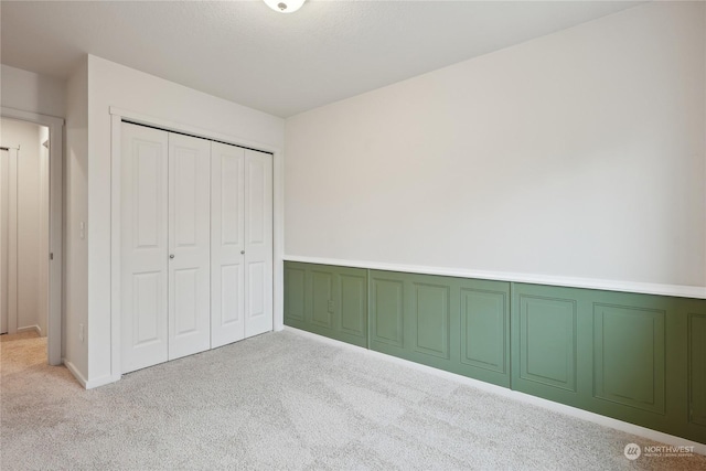 unfurnished bedroom with a closet and light carpet