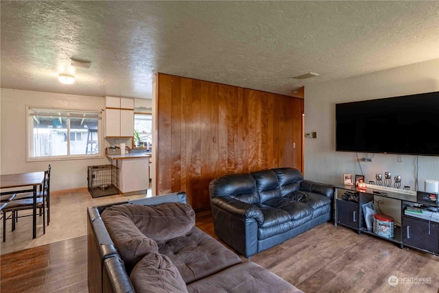 living room with a textured ceiling and light hardwood / wood-style flooring